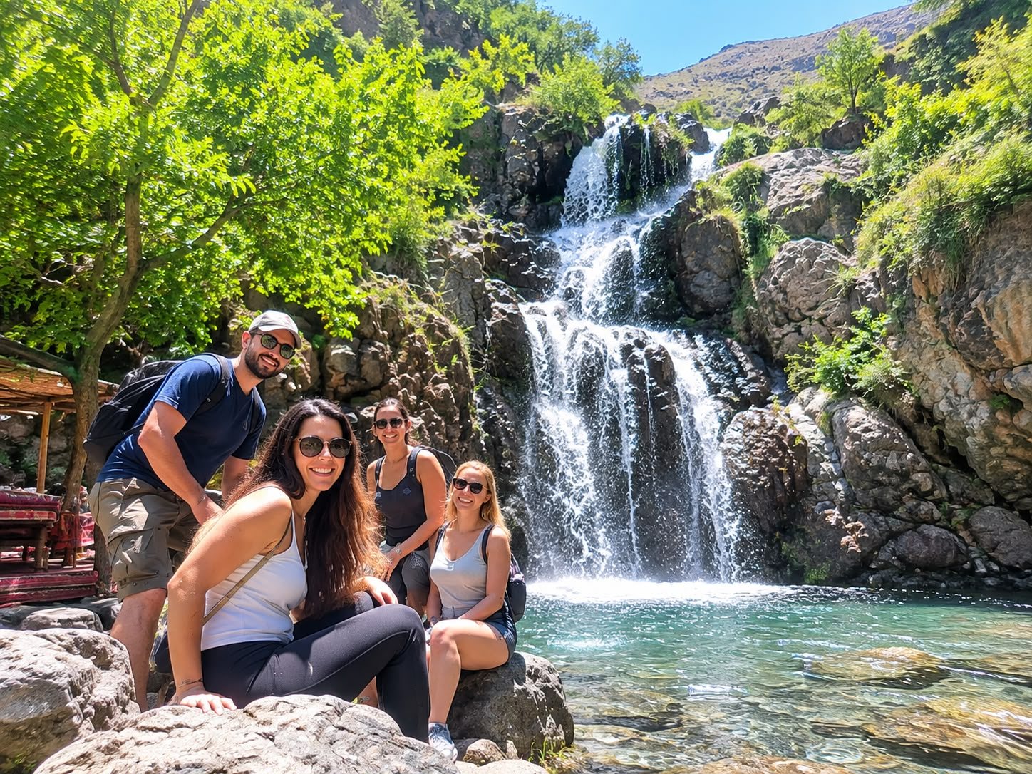 Travellers beside a waterfall in a green mountain setting