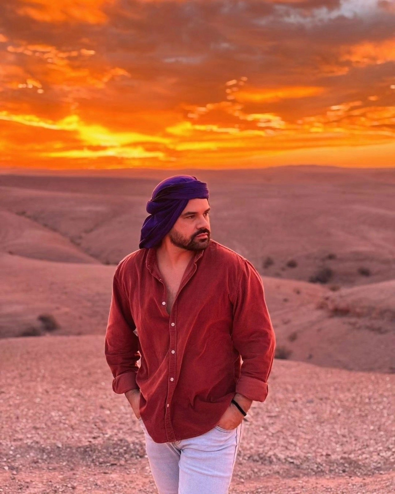 A man standing in a desert landscape at sunset