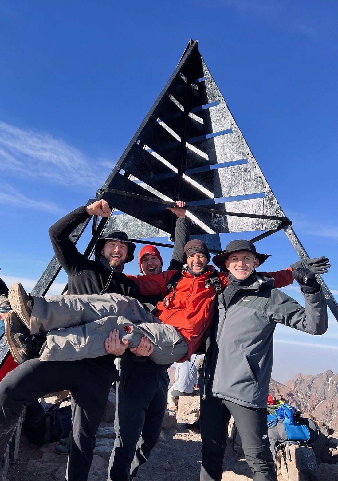 Hikers celebrating at a mountain summit marker