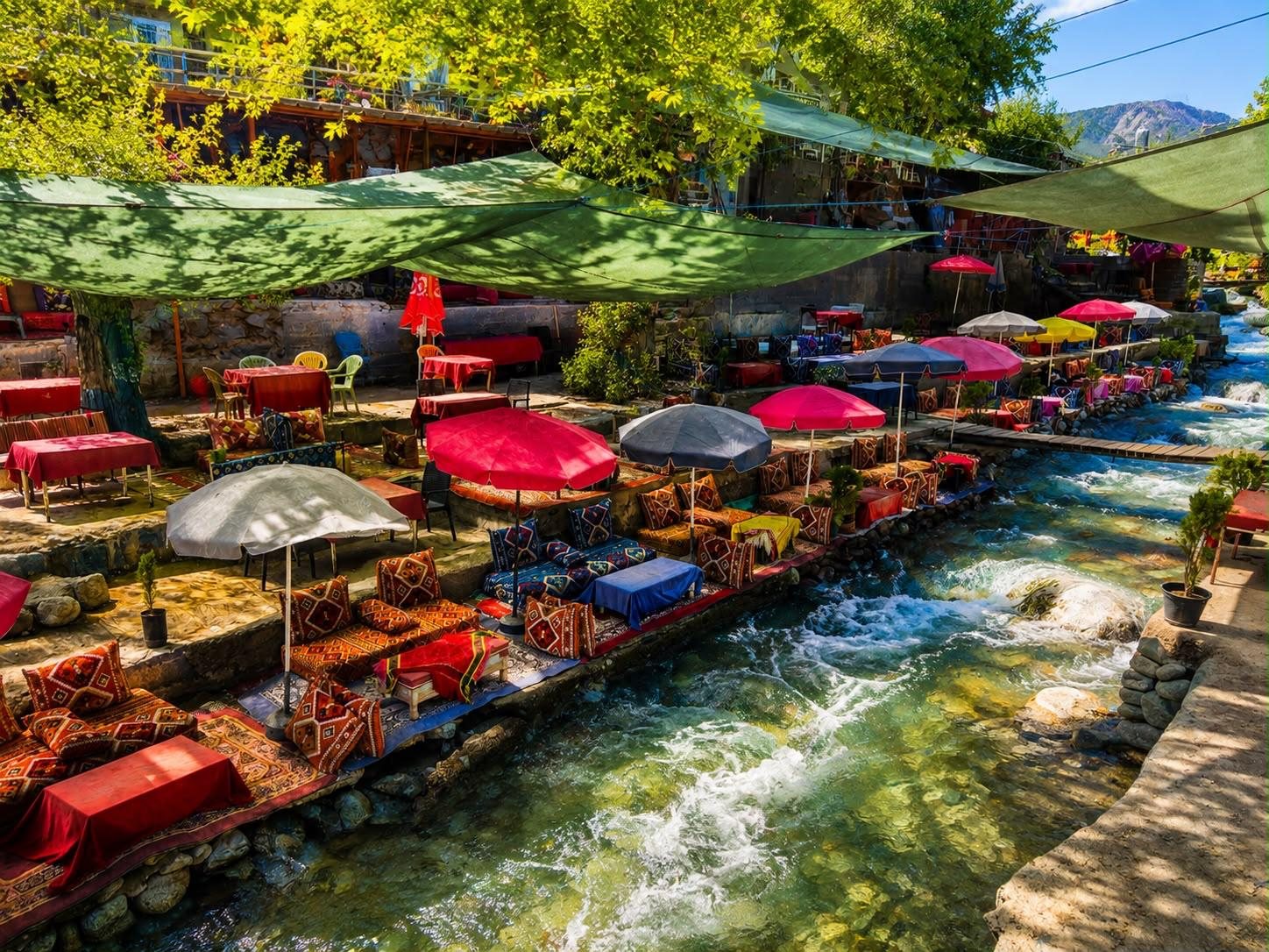 Outdoor tables beside a mountain stream in a green valley